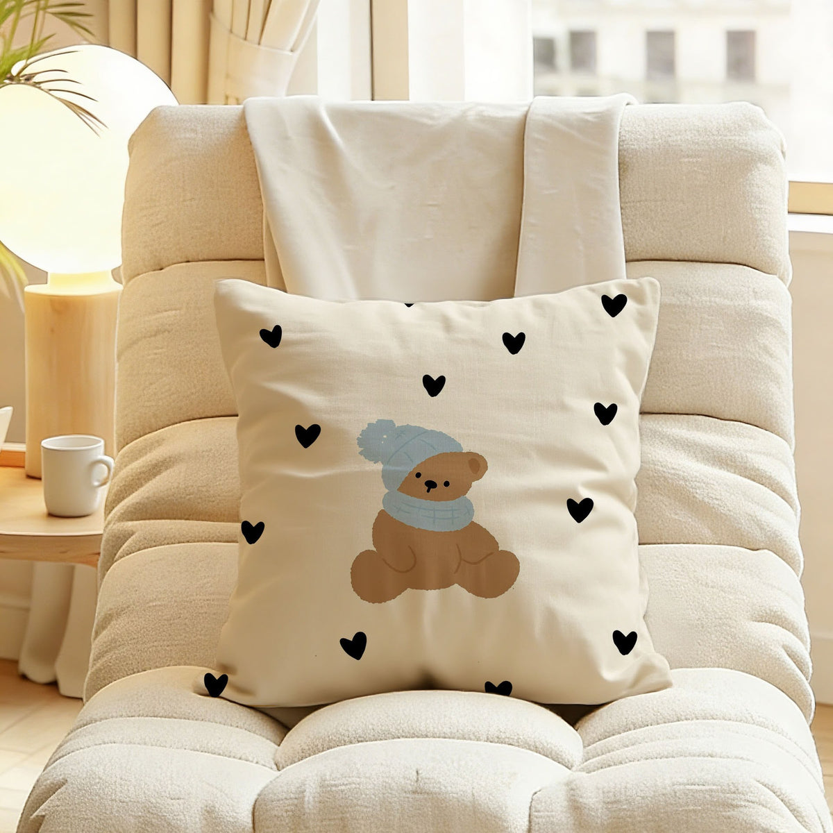 Tilda Teddy Hearts Cushion, cream cushion with a teddy bear in a blue bobble hat and scattered black hearts